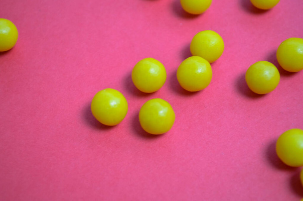 bright yellow vitamins of round volumetric form on a pink background. pills to strengthen human immunity in the midst of coronavirus and for health problems. flatlet from pills, background for drugs - Fotoğraf, Görsel