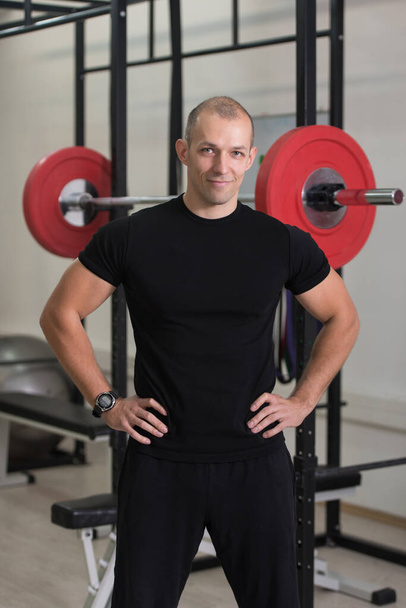 Portrait Of Personal Trainer In Sports Outfit In Fitness Center Gym Standing Strong - Foto, imagen