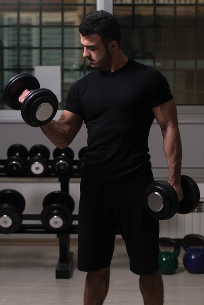 Man Working Out Biceps In A Gym - Dumbbell Concentration Curls - Foto, imagen