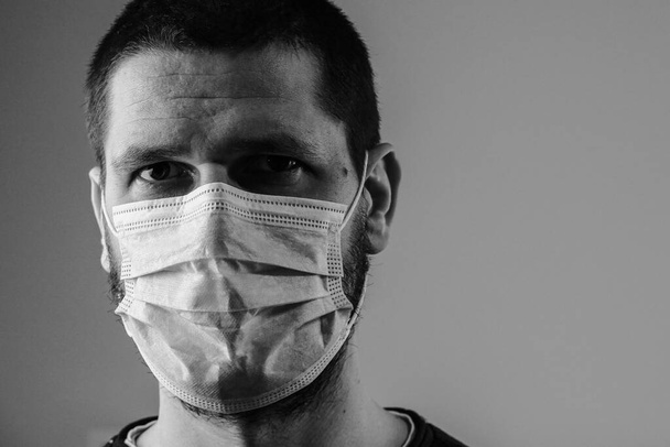 Close up black and white portrait of caucasian man adult wearing anti virus bacteria pollution protective mask head shot looking to the camera studio shot background - Photo, Image