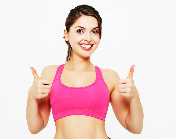 Portrait of a young fitness woman showing ok sign isolated on a - Foto, Bild