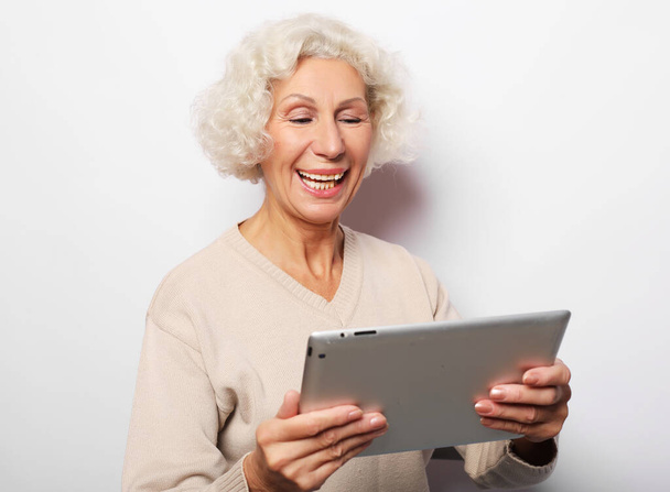 Happy mature woman using a tablet, communicates with children and grandchildren - Φωτογραφία, εικόνα