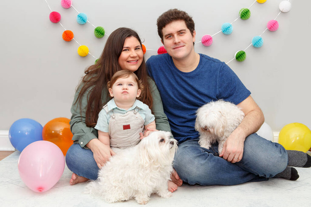 Kaukasische Familie mit Baby, das zu Hause seinen ersten Geburtstag feiert. Stolze Eltern Mutter und Vater zusammen mit Kleinkind und Hund als Haustiere. Happy Birthday Lifestyle-Konzept. - Foto, Bild