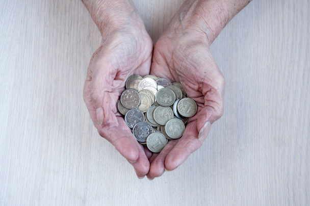 Old women's hands are small coins. The concept of pensions - Foto, afbeelding