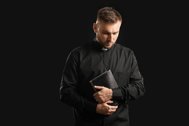 Mladý kněz s biblí na tmavém pozadí - Fotografie, Obrázek
