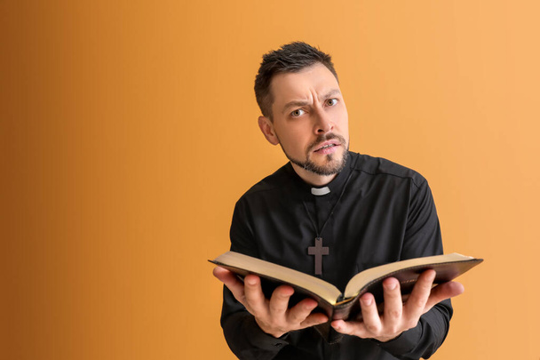 Hermoso sacerdote con Biblia sobre fondo de color
 - Foto, Imagen