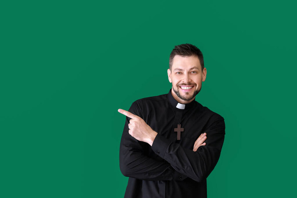 Красивий священик вказує на щось на кольоровому фоні
 - Фото, зображення