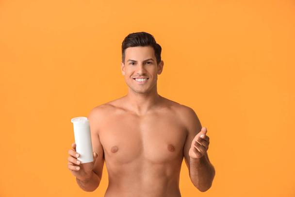 Young man applying sunscreen cream against color background - Foto, Imagem