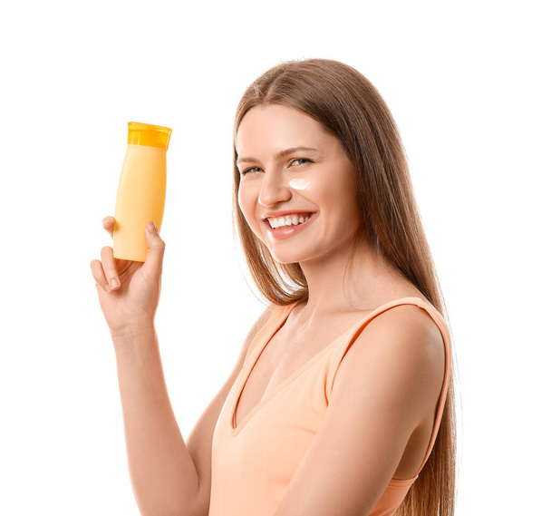 Young woman applying sunscreen cream against white background - Fotografie, Obrázek