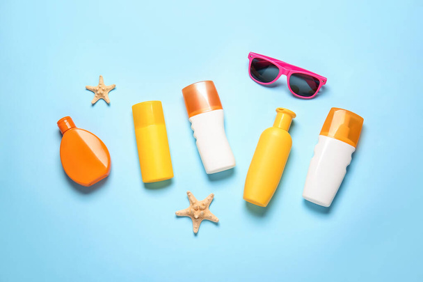 Bottles of sunscreen with sunglasses on color background - Zdjęcie, obraz