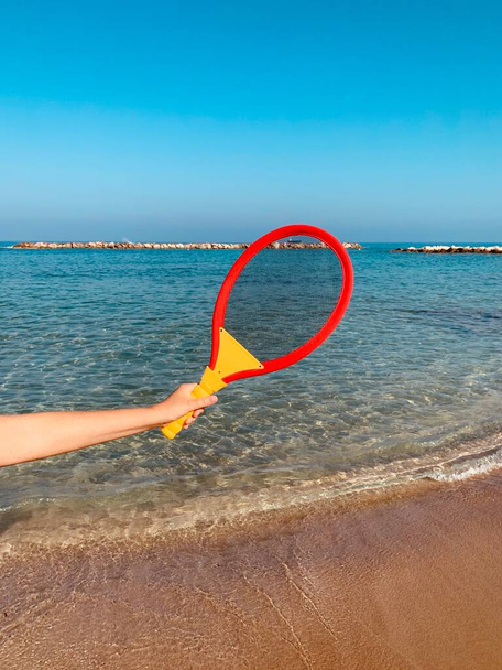 beach tennis racquet in female hand on beach - Photo, Image