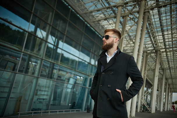 Success. Stylish young bearded man in coat, sunglasses businessman standing - Fotoğraf, Görsel