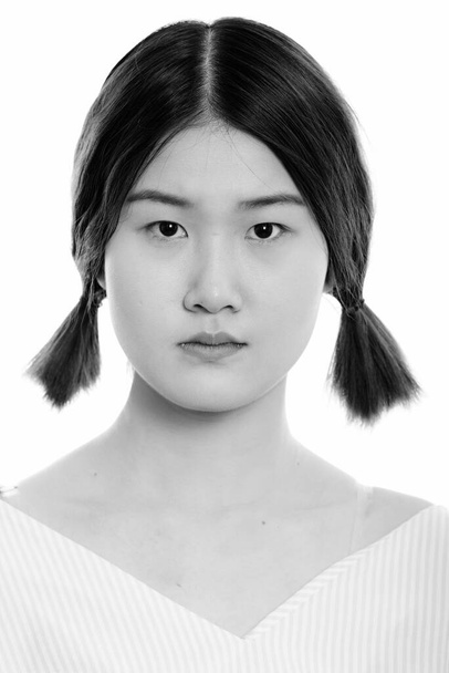 Studio shot of young beautiful Asian woman against white background in black and white - Foto, Imagem