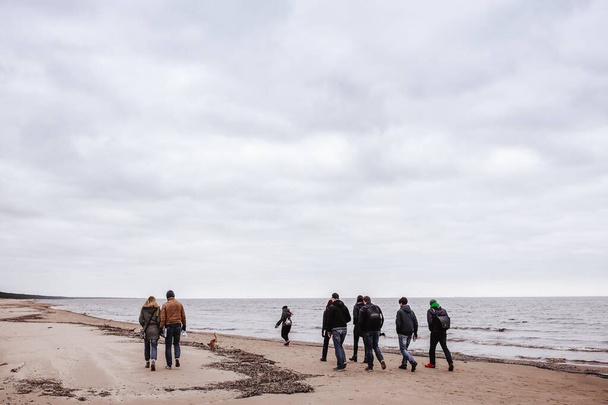 Varias personas caminando por la playa bajo el cielo nublado
 - Foto, Imagen