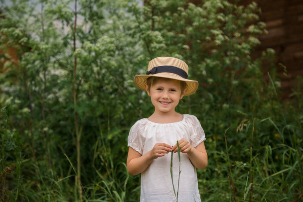 bambina in un vestito bianco boho con in belle boscaglie verdi di erba. - Foto, immagini