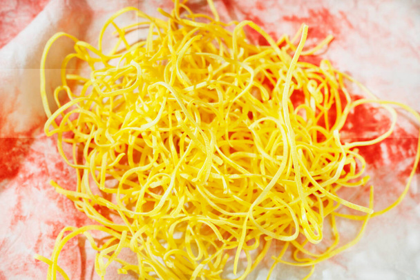 色の背景に調理されていないパスタフェットチーネ、卵と小麦粉で作られた黄色のフラット厚いパスタ - 写真・画像