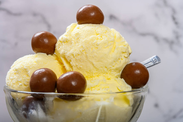 kom van vanille smaak ijs sundae met chocolade snoep close-up - Foto, afbeelding