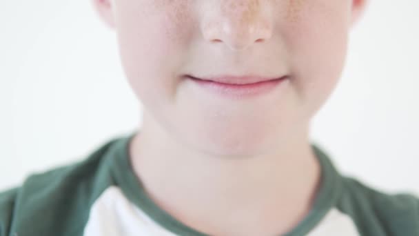 Zbliżenie uśmiecha się 8-letniego chłopca z uszkodzoną emalią na dolnym zębie - Materiał filmowy, wideo