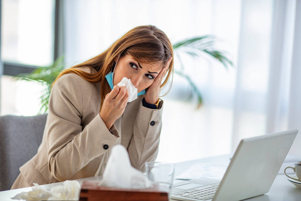 Shot of a frustrated businesswoman using a tissue to sneeze in while being seated in the office. Cropped shot of a businesswoman working in her office while suffering from allergies - Φωτογραφία, εικόνα