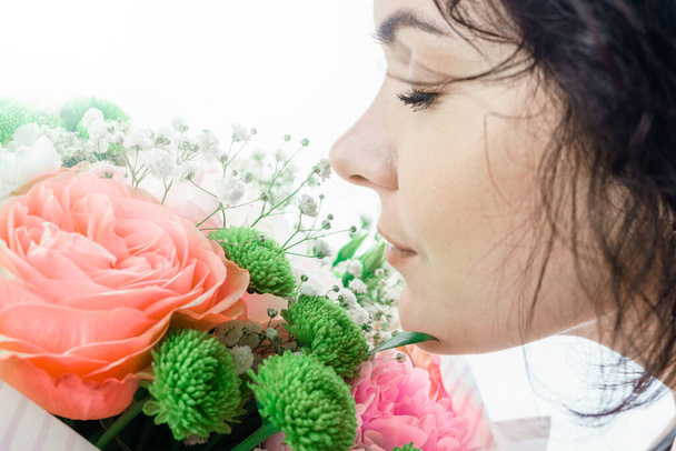 Portrait of sexy brunette model with evening makeup. Girl with a bouquet of flowers - Fotó, kép