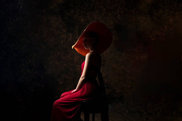 hermosa chica en un sombrero de color burdeos y en un vestido de noche de color burdeos posando sobre un fondo negro
 - Foto, imagen