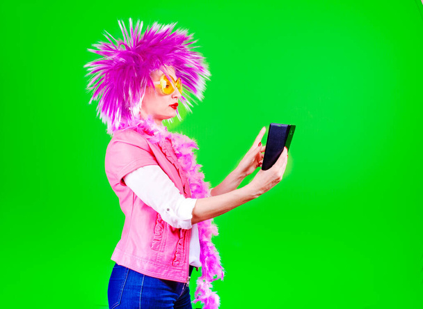 serious beautiful woman in a carnival wig writes a text message - Foto, Imagen