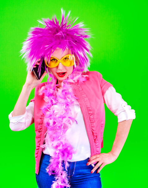 Mujer bonita con un pelo morado hablando en un teléfono móvil sobre un fondo verde
 - Foto, Imagen