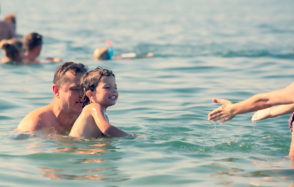 Father teaching his son how to swim. Father and son spending time together swimming in the sea. Vacation activities. Little boy is learning to swim. Family together. - Valokuva, kuva