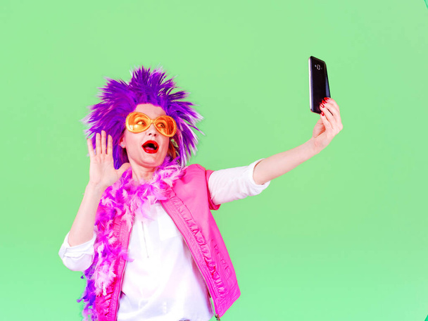Scamper woman in a party clothes do selfie on a light background - Foto, Imagen