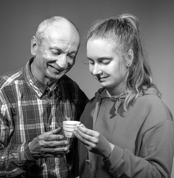 Abuelo con nieta disfrutando de una taza de café caliente fresco en el interior
 - Foto, imagen