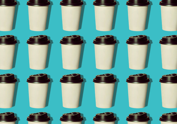 Coffee to go regular pattern made of photo on a turquoise background. Kraft paper cups with black lids and natural hard shadows. Lifestyle take away hot drinks concept. Trendy flatlay, top view. - Photo, Image