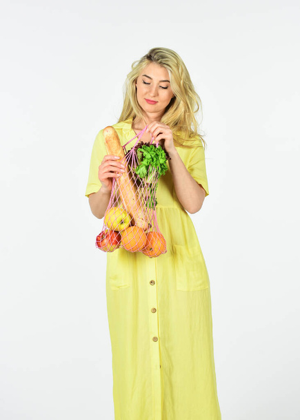 Conscious consumption. Eco trend. Zero waste concept. Girl in dress carry bag shopper. Woman holding string shopping bag with fruits. Reusable bag. Grocery store. Bag with groceries. Reusable eco bag - Foto, afbeelding