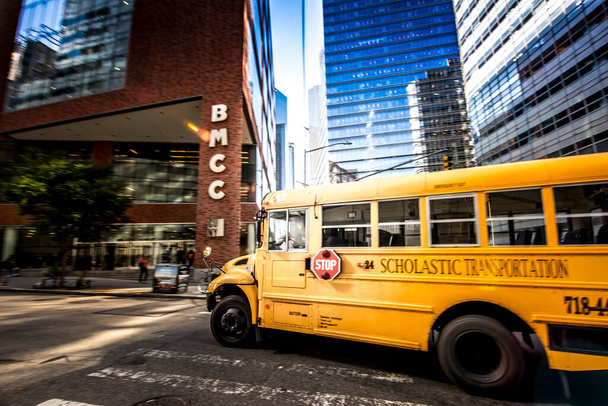 ÚJ YORK, USA - SZEPTEMBER 19, 2019: Iskolabusz költözik közel a Borough of Manhattan Community College. Élénk színek - Fotó, kép