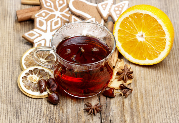 Glass of hot steaming tea among christmas decorations on wooden - Φωτογραφία, εικόνα