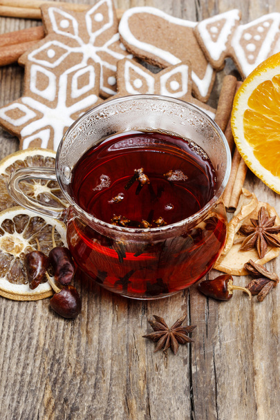 Glass of hot steaming tea among christmas decorations on wooden - Fotó, kép