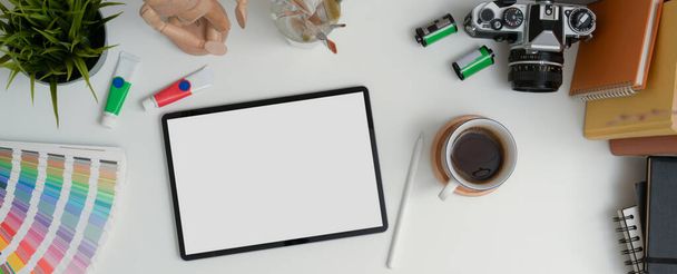 Vista superior da mesa de trabalho de designer com tablet mock-up, caneta, câmera, livros e ferramentas de pintura
 - Foto, Imagem