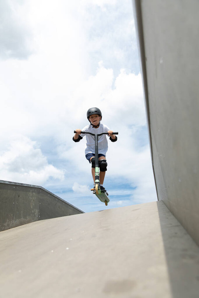 The boy jumps on a scooter - Foto, Imagen