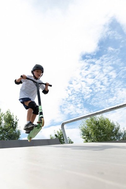 The boy jumps on a scooter - Fotó, kép