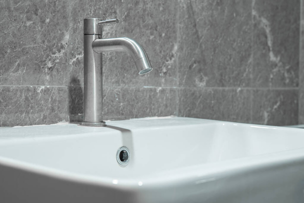 A tap or faucet on a white washbasin.Save water campaign. - Fotografie, Obrázek