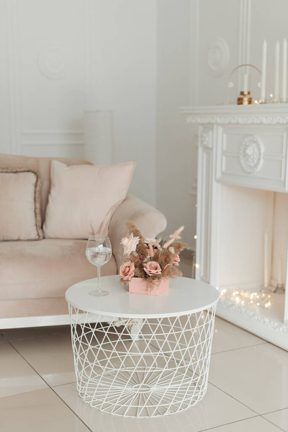 Artificial flowers in the interior. Decorative flowers in the interior. Artificial flowers in a vase. White interior of the room. Decorative fireplace.  - Foto, afbeelding