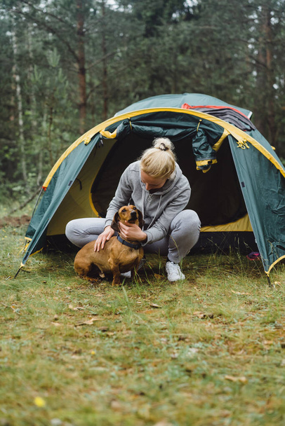 A young woman with a dog on a camping trip. Camping life concept. - Fotoğraf, Görsel