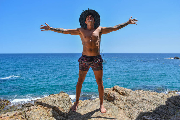 Człowiek stojący w krótkich spodenkach przed morzem cieszący się wakacjami - Zdjęcie, obraz