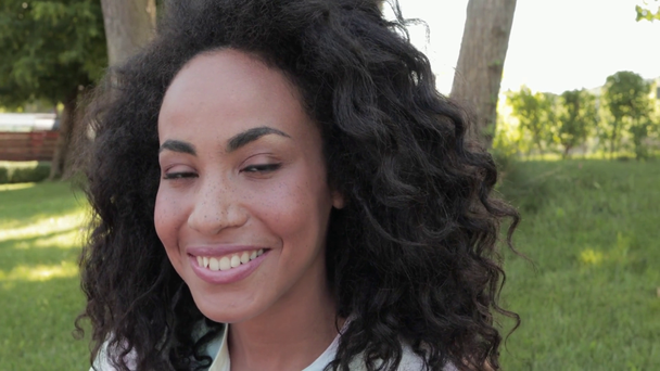 Veselý africký Američan žena drží kávu jít a usmívá se v parku  - Záběry, video
