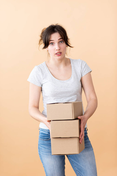 Surprised girl holds boxes in her hands on a beige background. Good delivery service - Fotó, kép