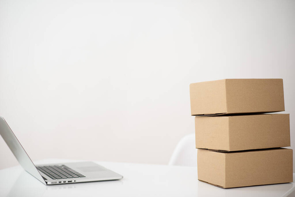 Photo of a table on which there is a laptop and a stack of cardboard boxes on the sides, with free space for text on a white background - 写真・画像