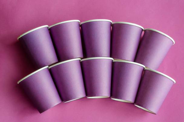 Geometrikus figura a kávéra való lila papírpoharakból. Eldobható szemüveg lila háttérrel. Környezetbarát ételek. Másold a helyet. Szelektív fókusz. - Fotó, kép