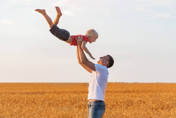 Father tosses child boy high into sky. Dad and son having fun on outdoors.. - Foto, afbeelding