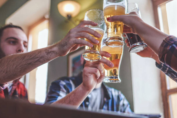 Vrienden die bier drinken en glazen aftappen in bar of pub - Foto, afbeelding