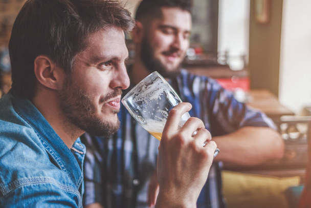 Bier drinken. Vriendengroep genietend van een biertje in de pub, toasten en lachen. - Foto, afbeelding