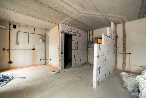 Interior de una habitación de apartamentos con paredes desnudas y techo en construcción. - Foto, imagen